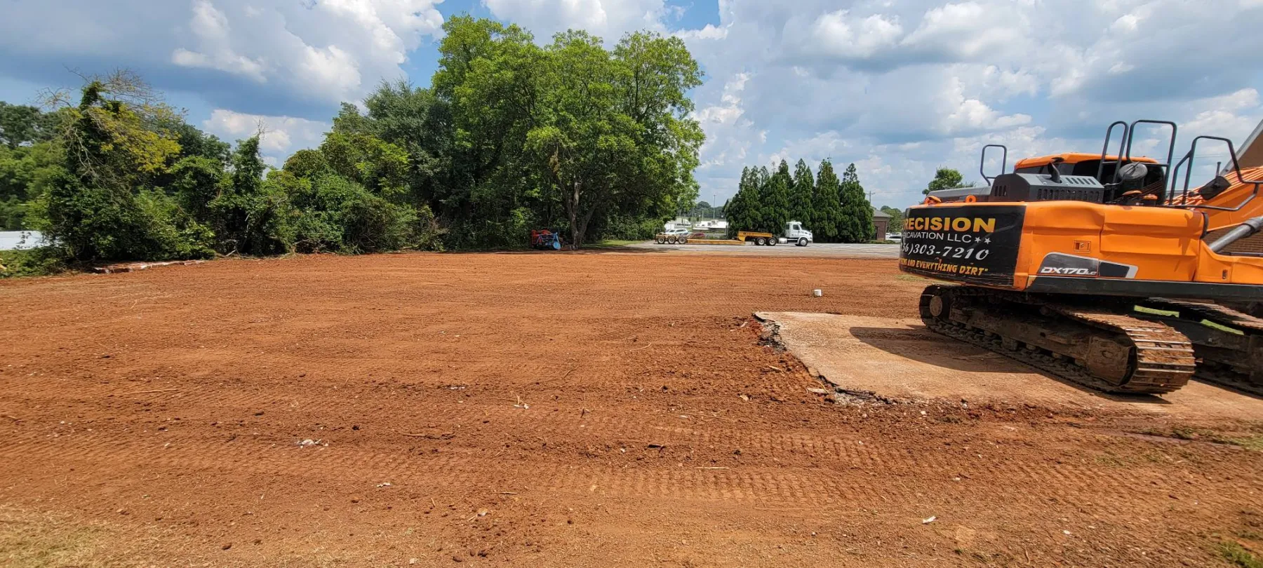 Graded lot after a teardown, our trackhoe parked on the last of the old slab