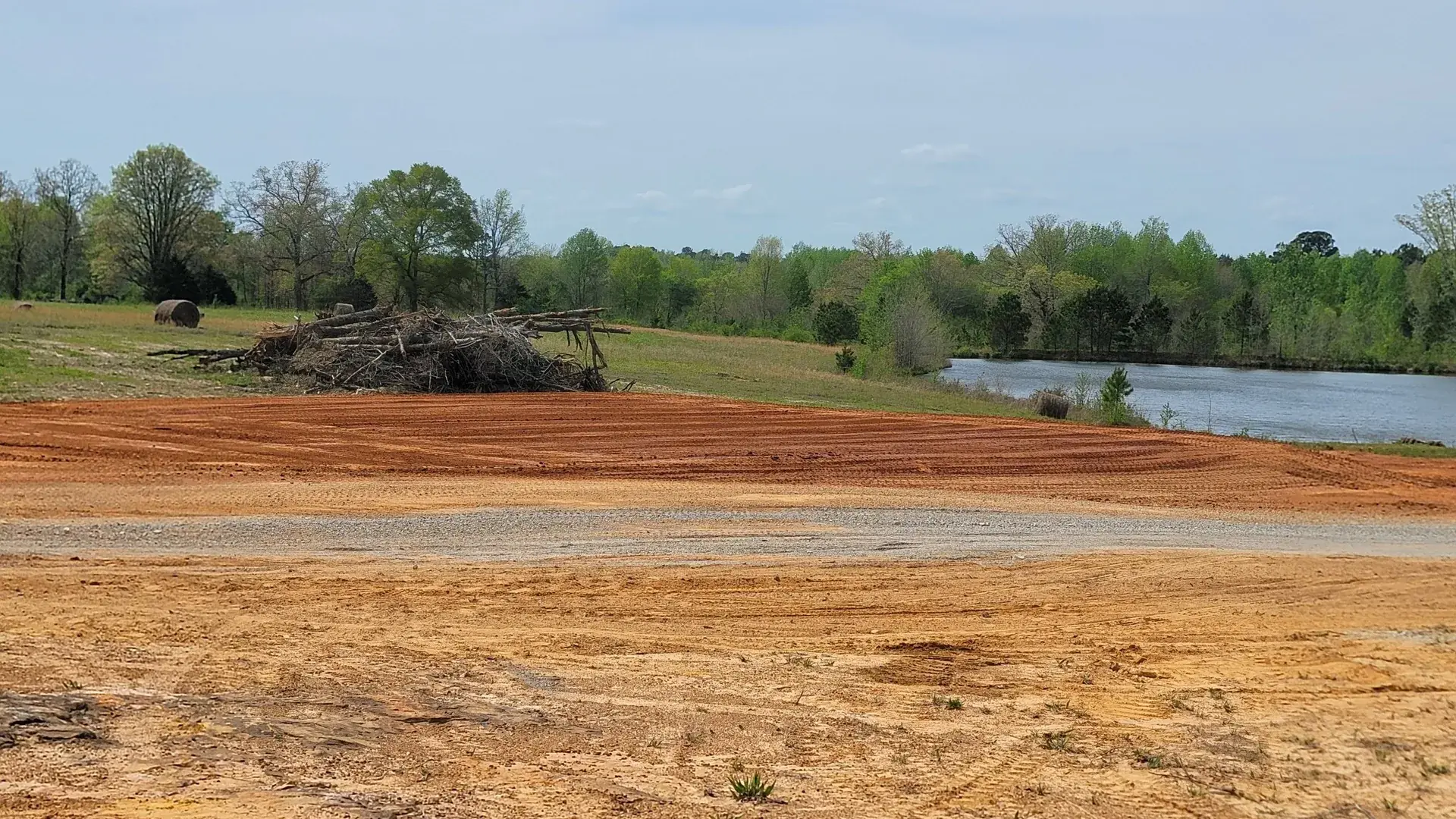 Red clay ground cleared and graded for a house pad near the water, the kind of lot we work around Guntersville