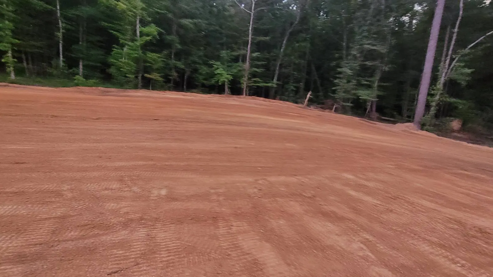 Red clay pad graded out at the edge of the woods, the kind of lot we work around Russellville