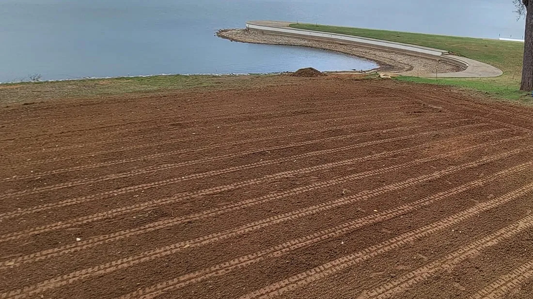 A lakefront lot leveled and raked smooth after new French drains went in, the lake beyond