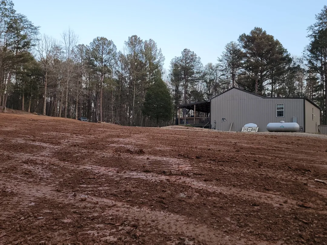 Yard graded smooth beside a metal shop so rain runs away from the building