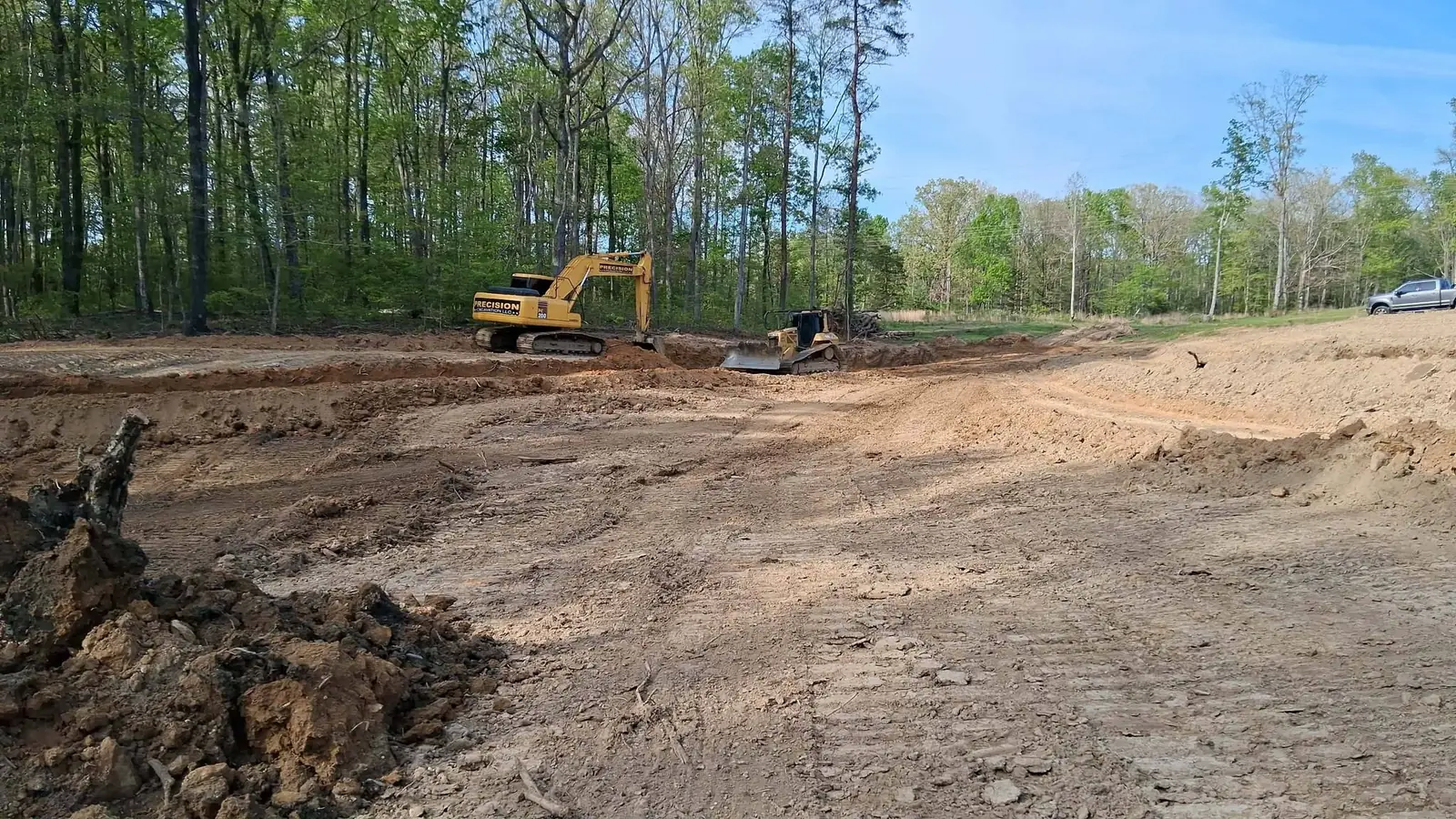 Our lettered trackhoe and a dozer shaping a new pond basin on a wooded North Alabama job